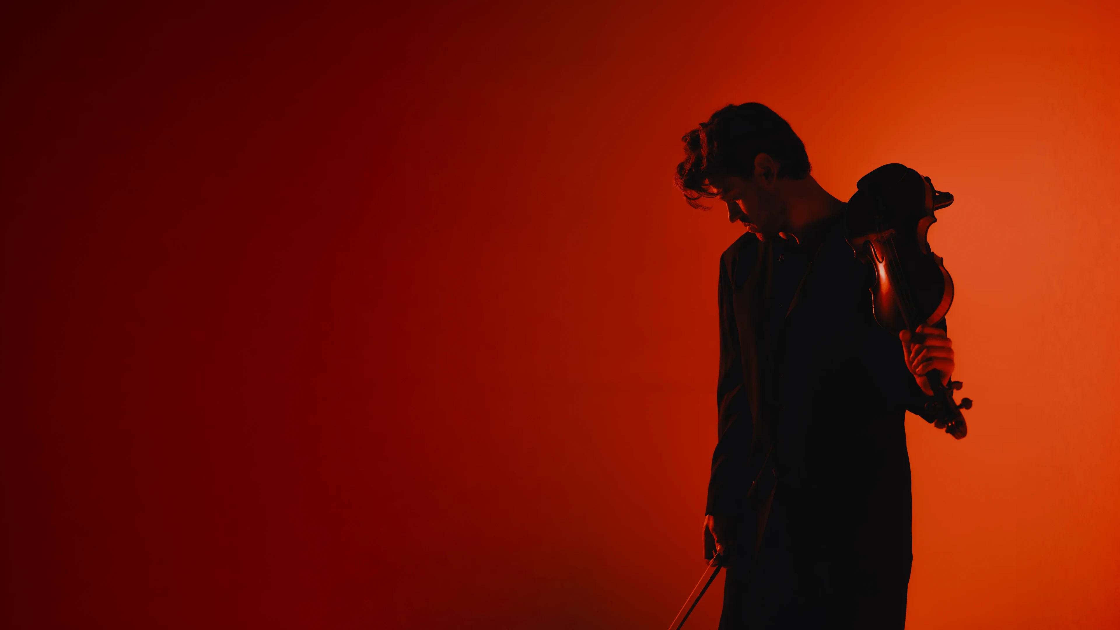 Blake Pouliot holding his violin against an orange background